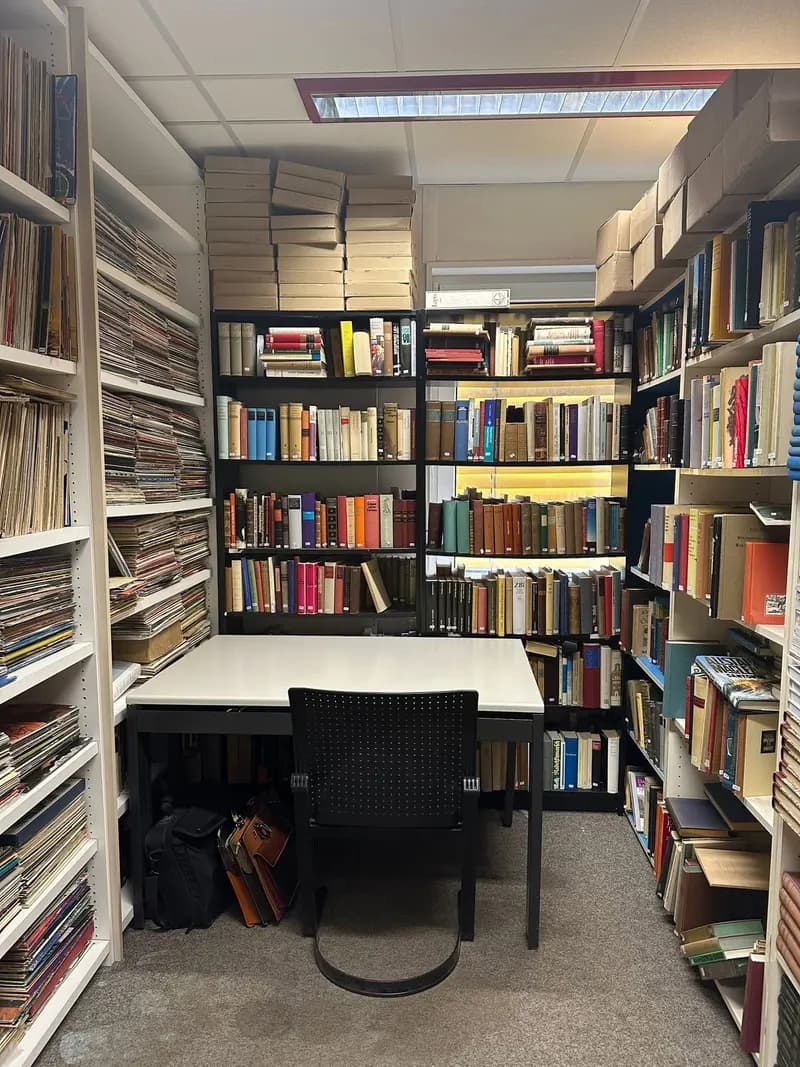 Blick in unser Lager: Arbeitsplatz zwischen vollen Bücherregalen